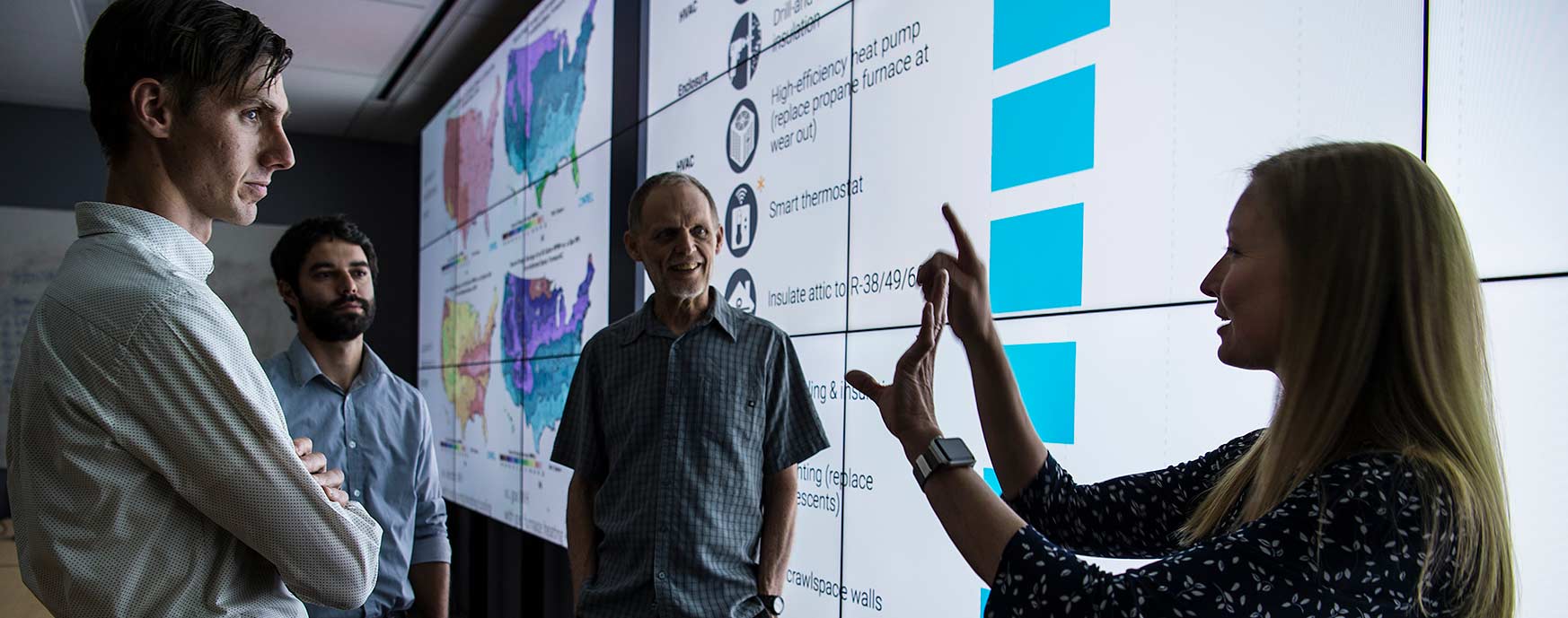 Photo of a group talking in front of a large display of information.