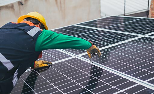 Photo of a person installing rooftop solar on a house.