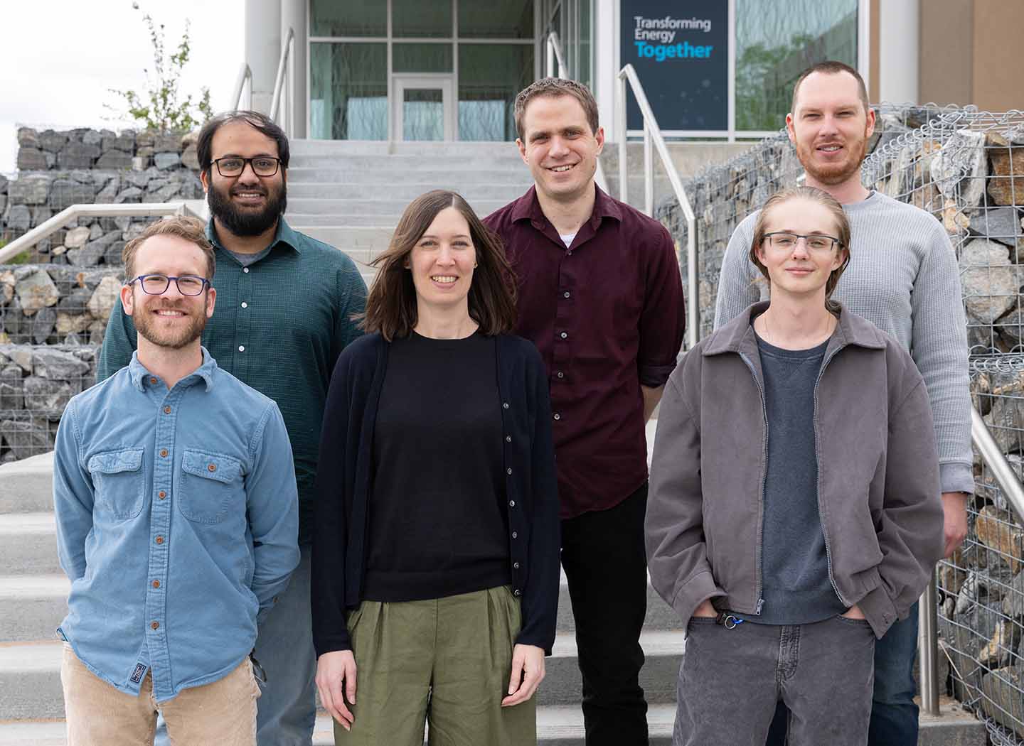 Six people stand on steps outside a building.