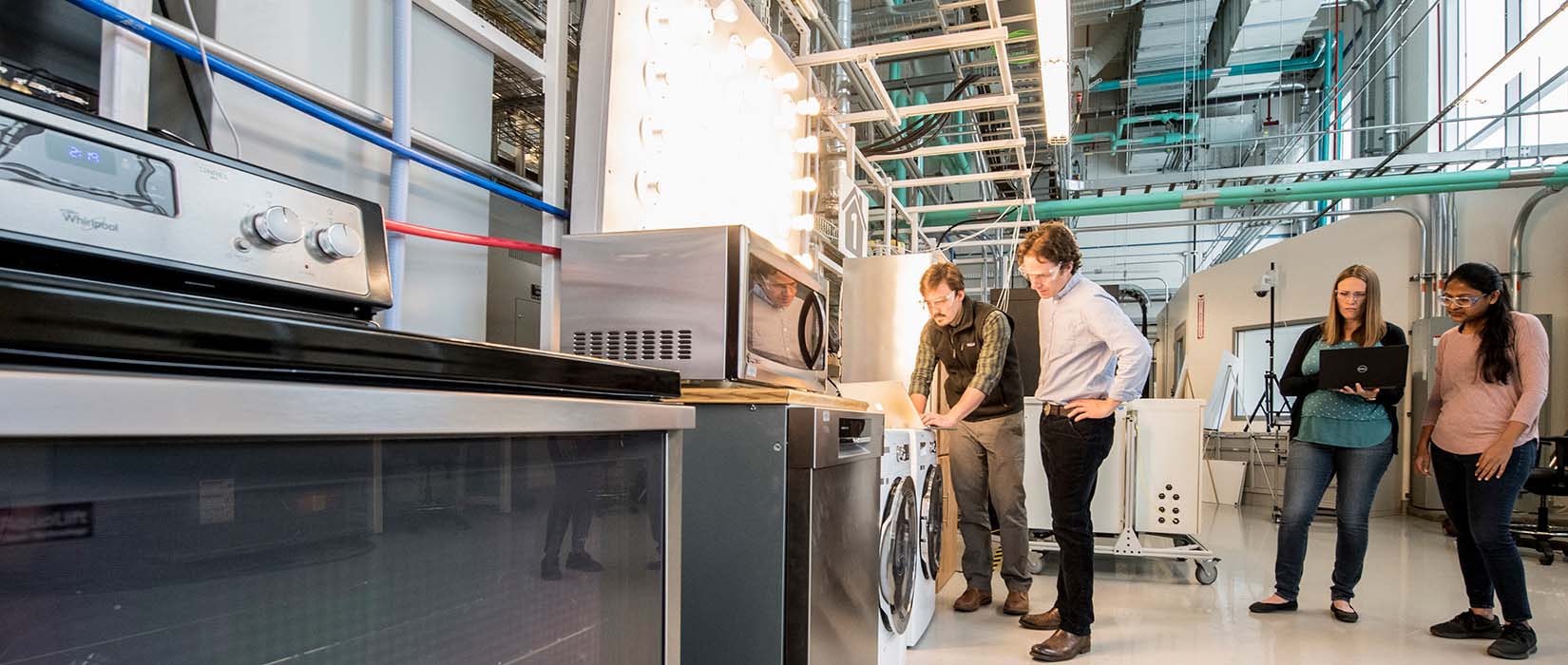 Four people researching appliances in a lab. 