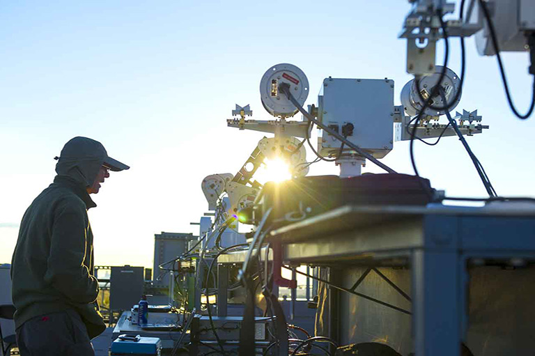 Person stands next to solar radiation measurement tool outside