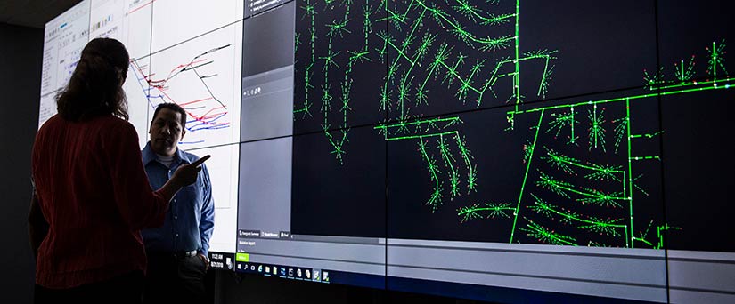 Researchers discuss a large projection of a power system.