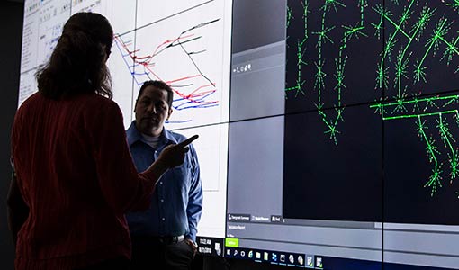 Researchers discuss a large projection of a power system.