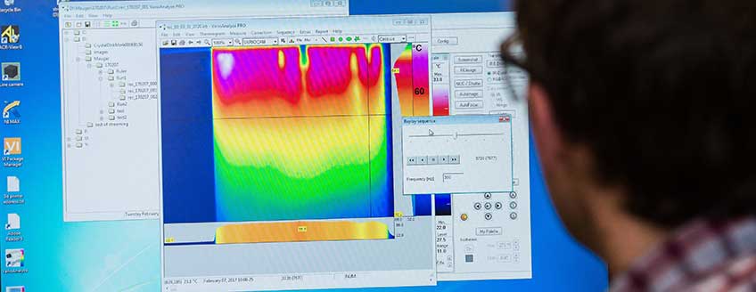 Photo of man looking at a large computer monitor with a colorful, visual display of data.