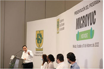 Yucatán Governor, Mauricio Villa speaks at podium in front of panel