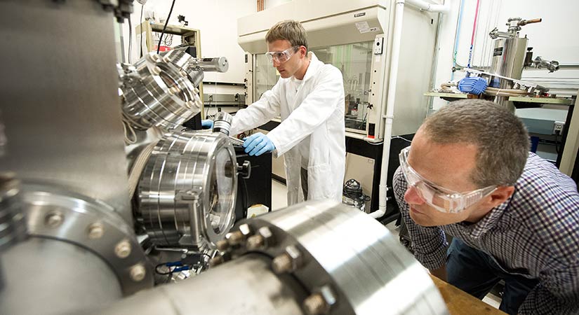 Four researchers stand in front of a large, black, cabinet-like computing device.