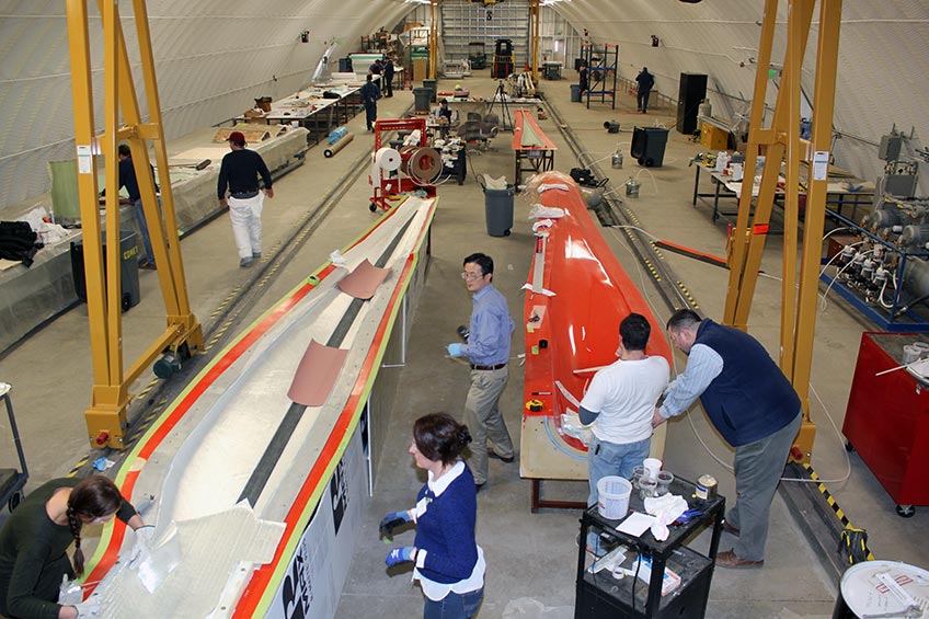 Photo of people working on turbine blades in a dome-shaped building.