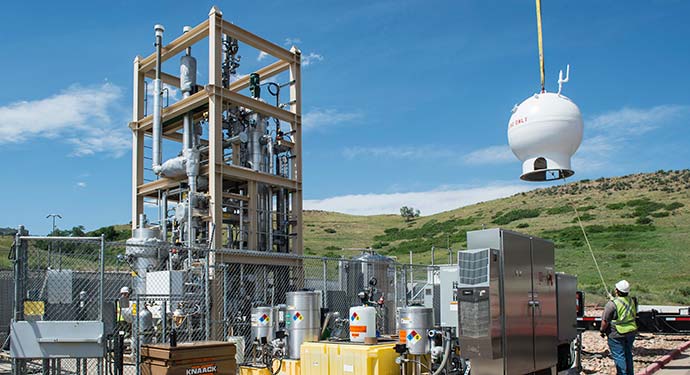 Crews crane a natural gas storage vessel into place in a bioreactor.