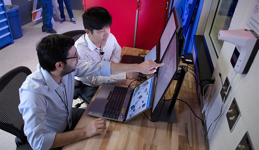 Two people at a table looking at computers.