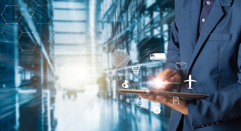 A close-up photo of a businessperson holding a tablet in a warehouse. 