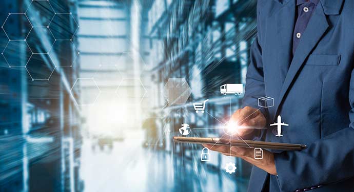A close-up photo of a businessperson holding a tablet in a warehouse.