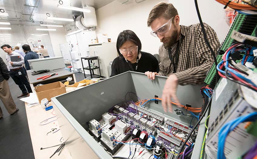 A man and a woman work on a wired machine