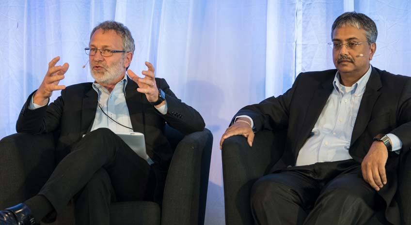 Photo of two men sitting in armchairs on a stage.