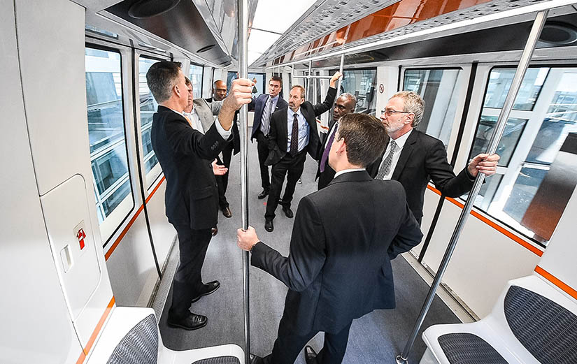 A group of people rides an airport shuttle train
