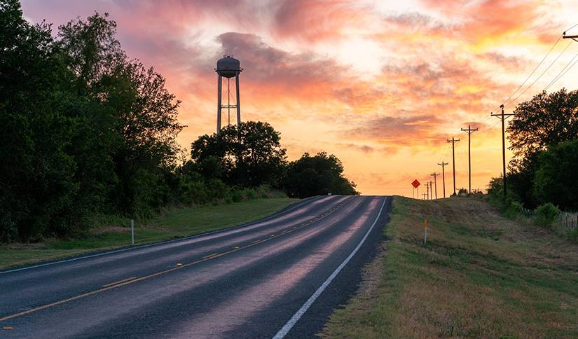 Photo of a rural highway with colorful sky in background