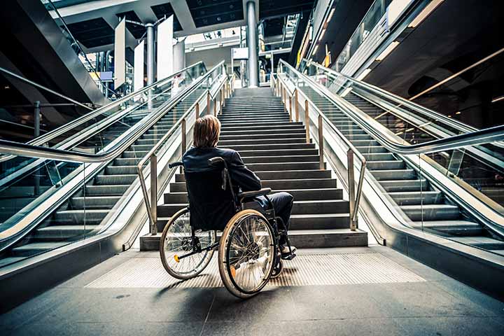 Businessman on a wheelchair in front of stairs