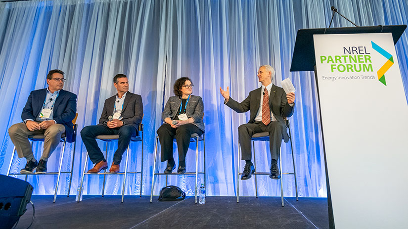 Four people sit on a stage.