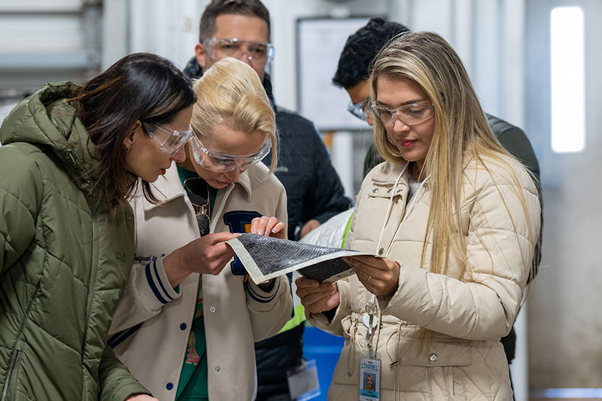 A group of people examining a sample of fabric material.