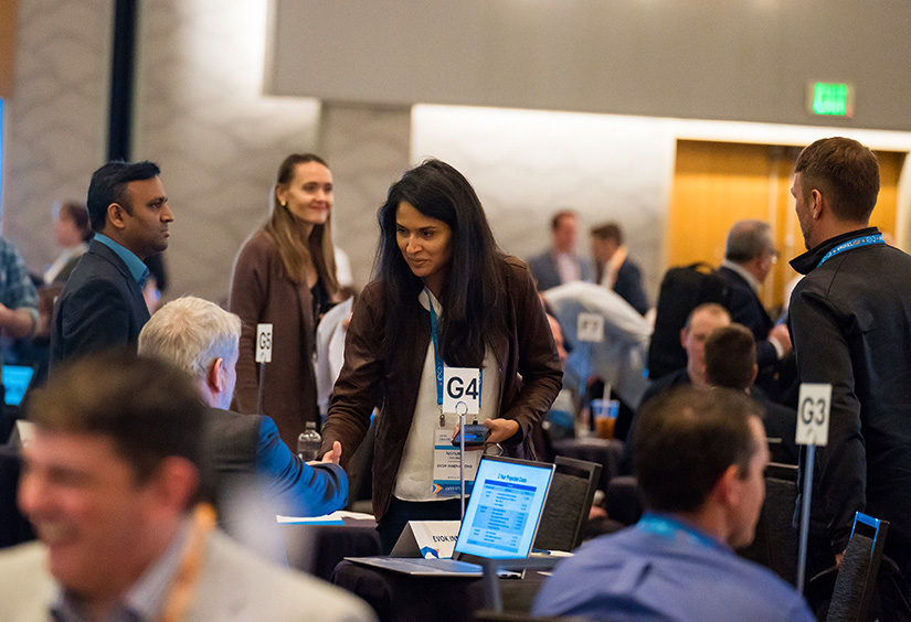 A group of people sit at small tables in a ballroom.