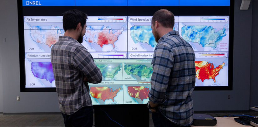 Two men looking at multiple screens.