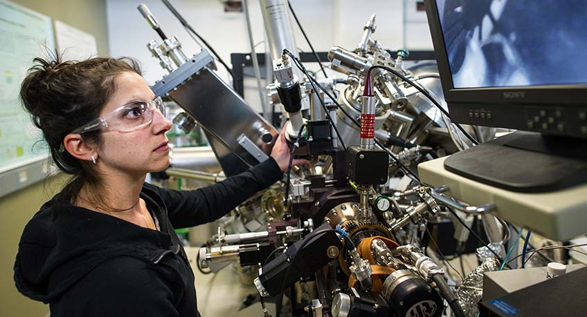 A woman studies images on a computer screen.