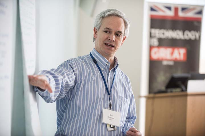 Photo of man pointing to notes on a whiteboard.