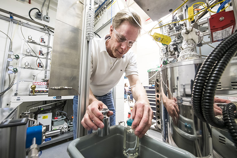 Photo of a researcher working with bottles in a lab