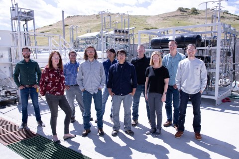Ten people involved in the IHS project stand in front of the fueling equipment.