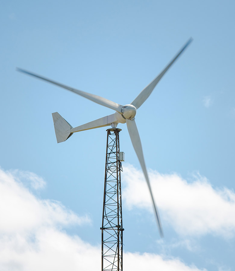A small wind turbine against a cloudy blue sky.