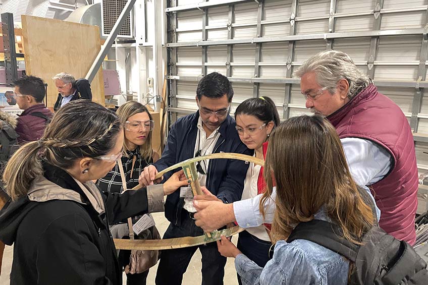 A group of people with safety goggles examine a piece of wind turbine materials.