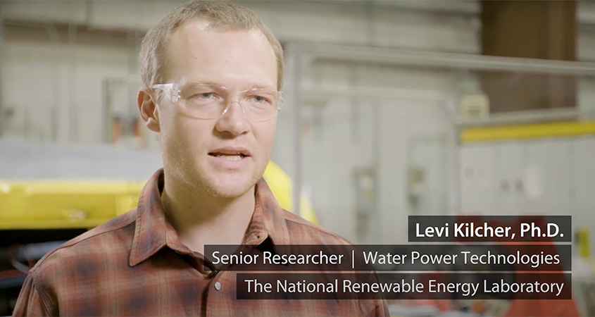 Levi Kilcher talks while wearing clear goggles and sitting in a warehouse in front of mechanical equipment overlain by his name and title.