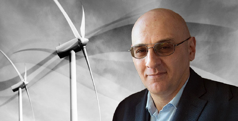 A headshot of Vahan Gevorgian in front of two wind tubrines.