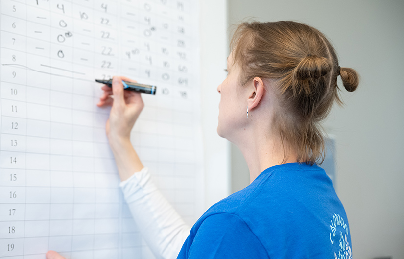 A person writes on a whiteboard.