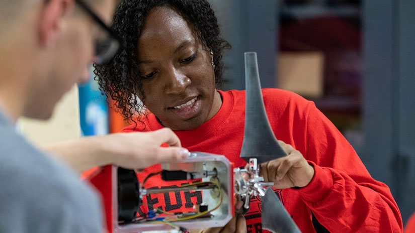 Two people work on a wind turbine model