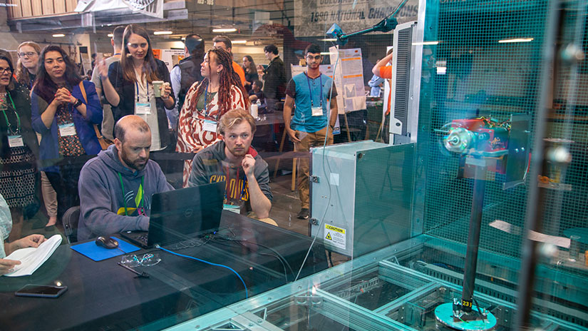 Jason Roadman, surrounded by students, observes a model turbine as it spins inside a testing tunnel.