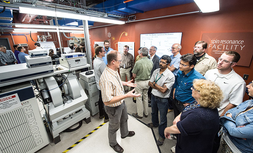 A group of people standing and talking in a lab. 