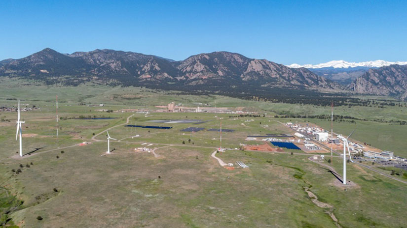 An aerial view of three wind turbines on NREL’s Flatirons Campus with the Rocky Mountains in the background