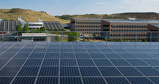 Photo of a solar PV array on a rooftop of a building with a view of many buildings in the background.