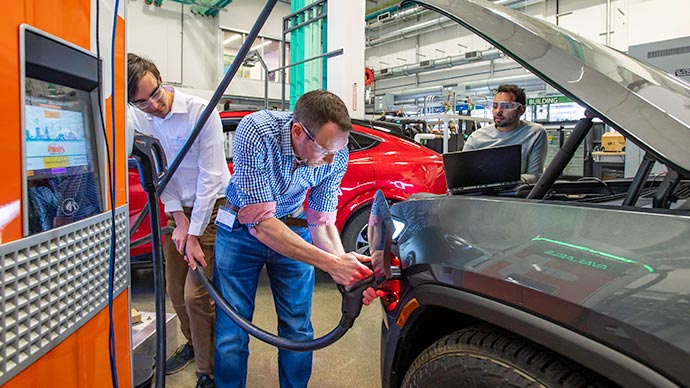 Researchers in a lab gather data from an EV charging station connected to a pickup truck.