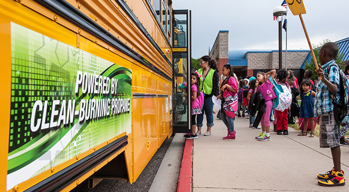 Children stand in line to get on a school bus.