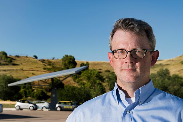 Head shot of a researcher in front of a hill with shrubs.