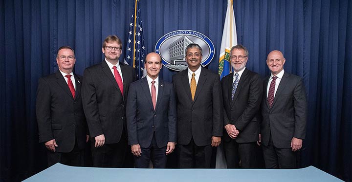 Six men in suits stand together to sign a contract for their new partnerships