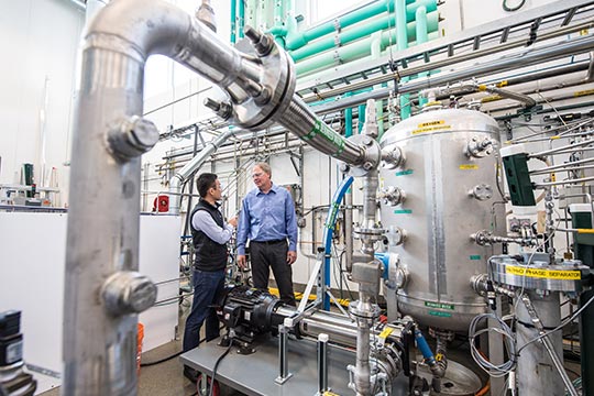 Two men talk in a laboratory.