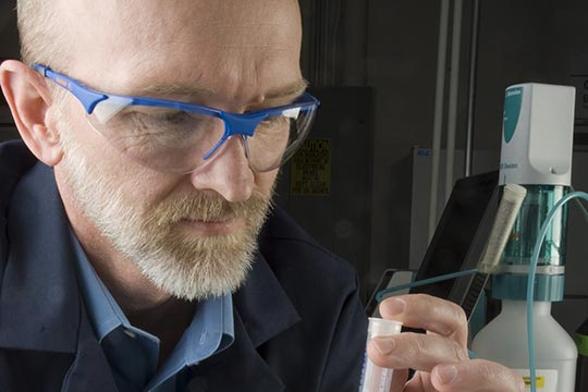 A person working with test tubes in a lab.
