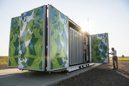 A man standing next to a large stationary battery.