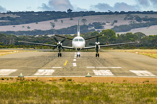 A small airplane lands on a runway in rural America.