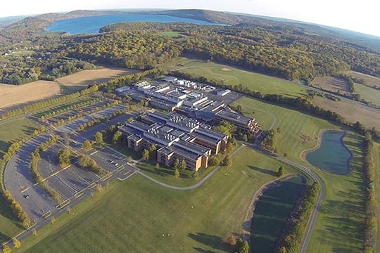 Aerial view shows large corporate campus in the middle of a wooded area.