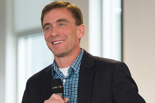 A picture of a smiling man holding a microphone.