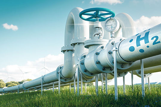 A large outdoor fuel tank with wind turbines in the background.