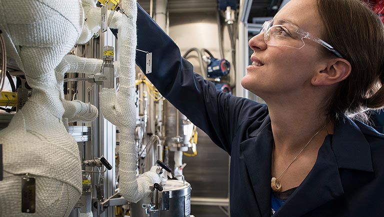 Photo of a researcher working with a plug flow reactor in a lab